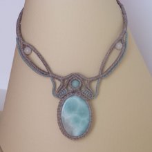 Ketting in taupegrijs/roestblauw micro-macramé met een natuurlijke edelsteen in zachte tinten wit en lichtblauw als middelpunt.